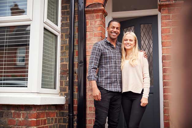 Young couple standing outside new home